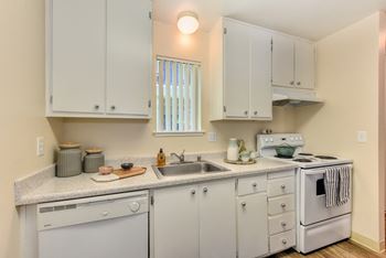 Kitchen with white cabinets and appliances, including dishwasher and stove/oven. at Renaissance Park Apartments, California
